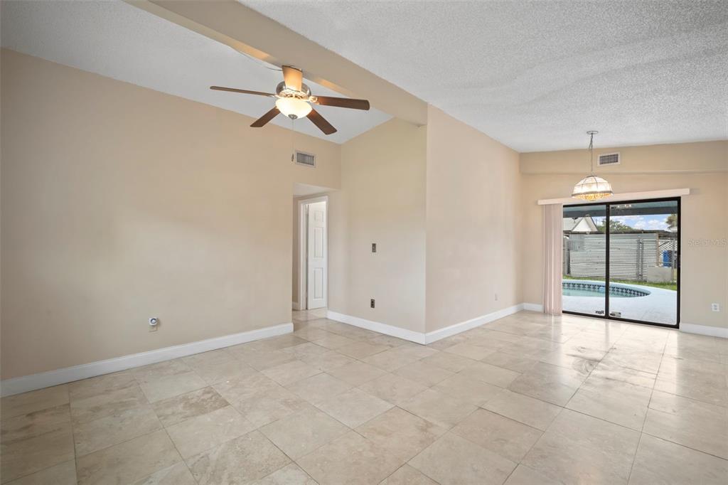 4712 Bessie Road Tampa, FL 33615 - Photo 9 of 28 an empty room with chandelier fan and windows
