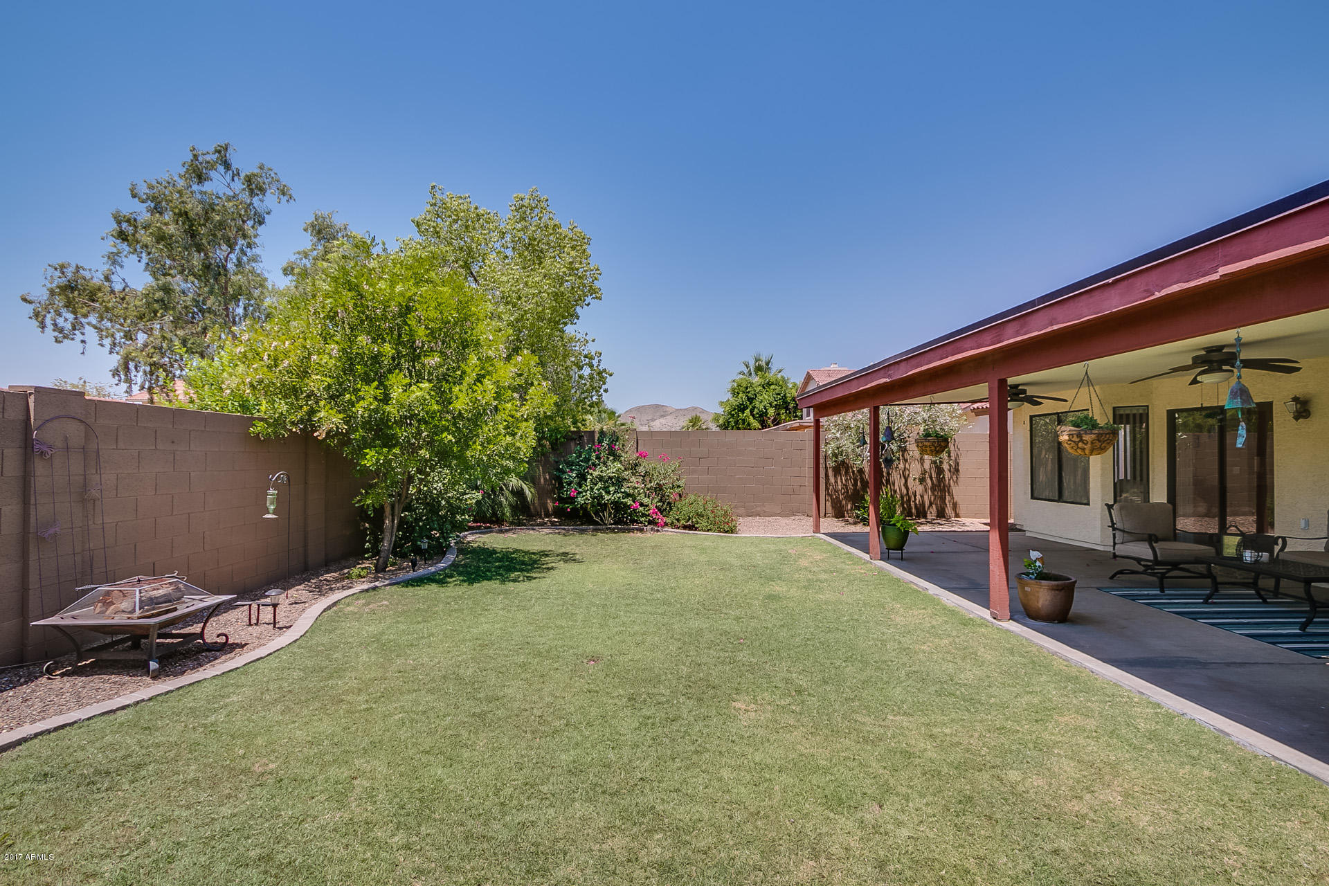 3623 East Agave Road Phoenix, AZ 85044 - Photo 35 of 41 a backyard of a house with table and chairs potted plants and a large tree