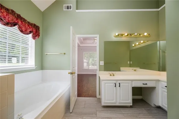 a bathroom with a tub sink and mirror