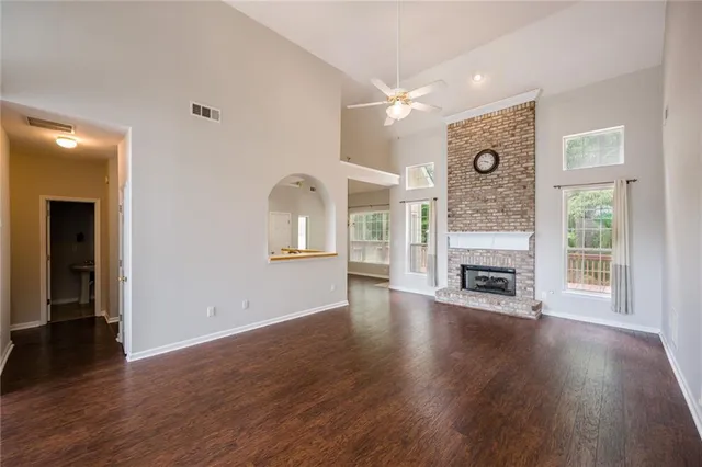 an empty room with wooden floor fireplace and windows