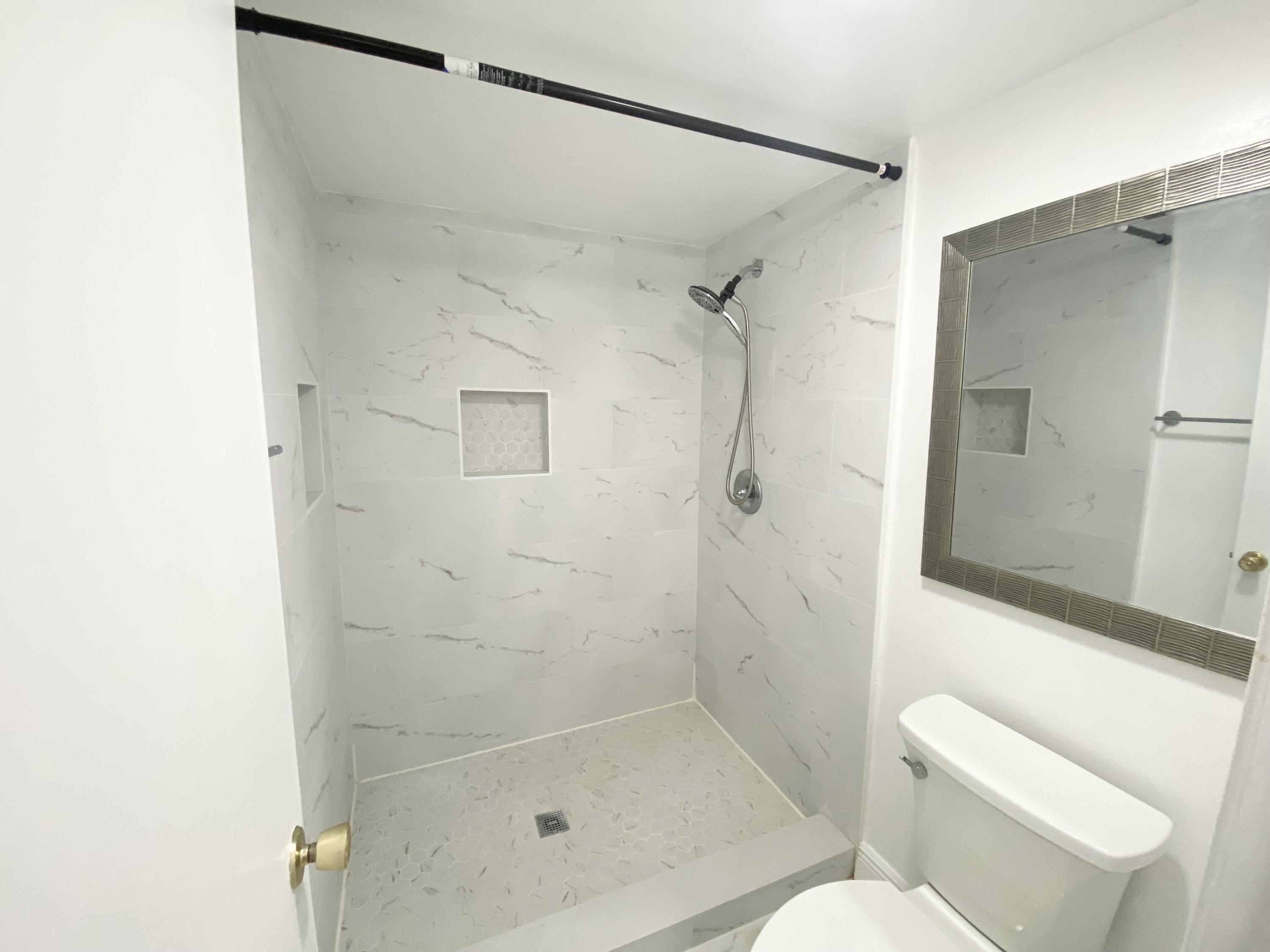 1100 Boxwood Drive, Unit 101 Delray Beach, FL 33445 - Photo 13 of 33 a bathroom with a shower and toilet