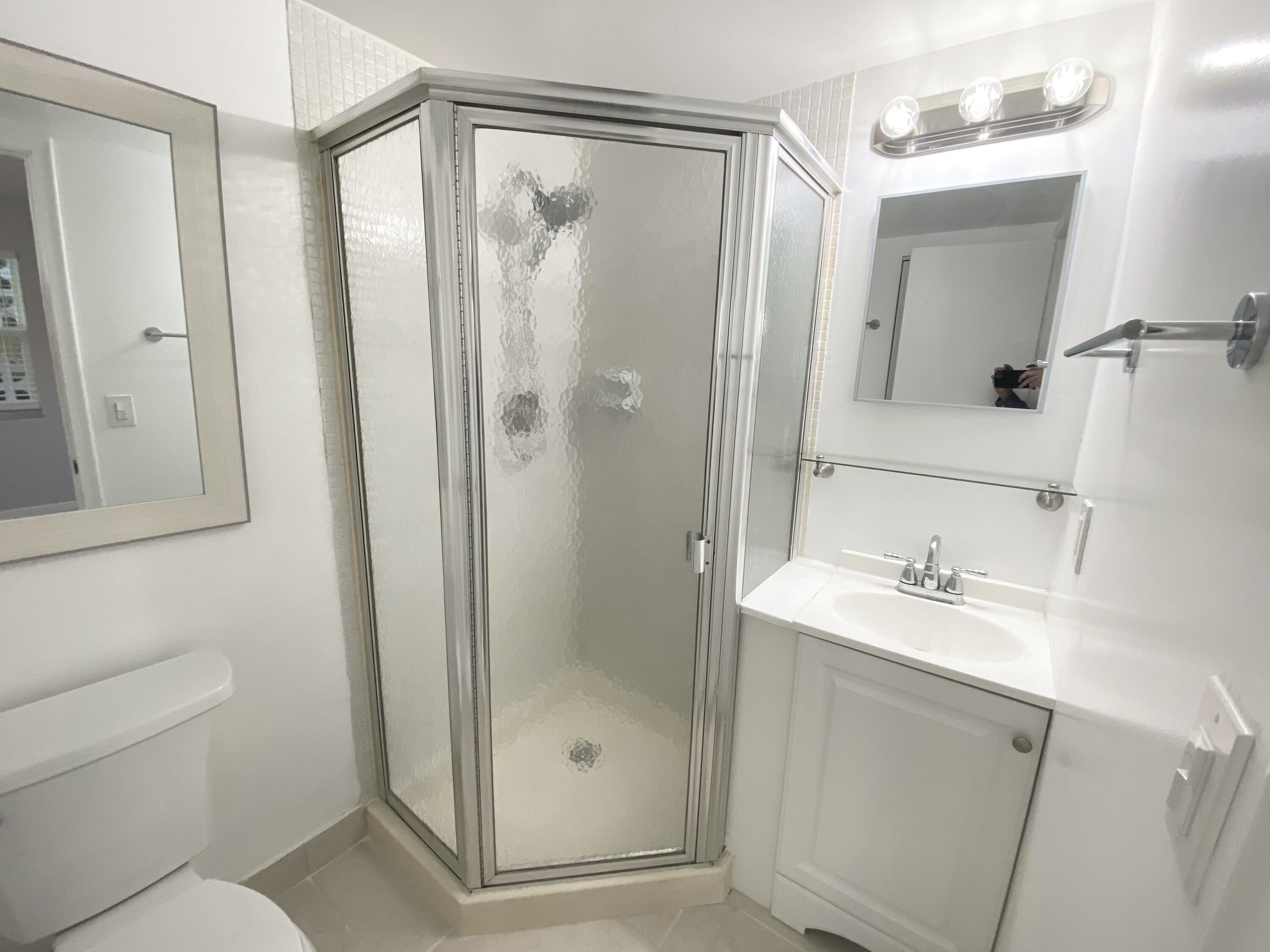 1100 Boxwood Drive, Unit 101 Delray Beach, FL 33445 - Photo 16 of 33 a bathroom with a shower sink vanity and mirror