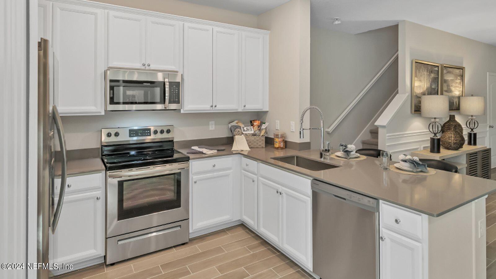 4338 Leeward Breeze Loop Middleburg, FL 32068 - Photo 2 of 13 a kitchen with stainless steel appliances granite countertop a sink stove and microwave