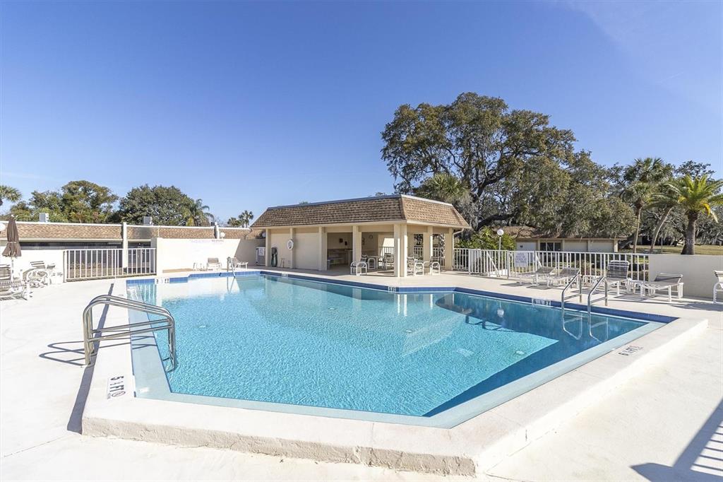 11410 Carriage Hill Drive, Unit 1 Port Richey, FL 34668 - Photo 34 of 63 a view of a swimming pool with a lounge chair
