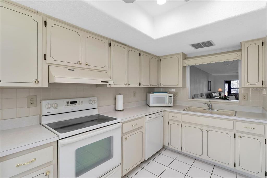 11410 Carriage Hill Drive, Unit 1 Port Richey, FL 34668 - Photo 7 of 63 a kitchen with white cabinets and white appliances