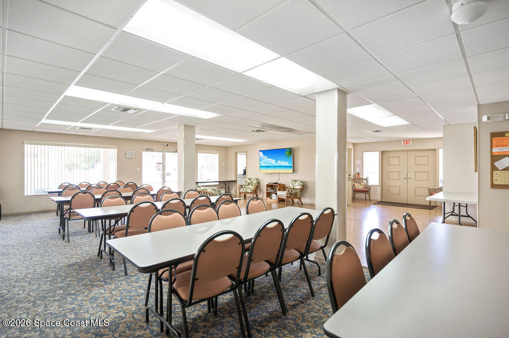 150 Intrepid Way, Unit 8D Cape Canaveral, FL 32920 - Photo 31 of 36 a room with lots of tables a large window and chairs