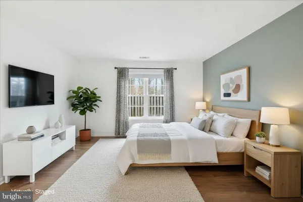 a bedroom with a bed a flat screen tv and a potted plant