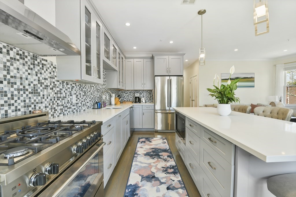 a kitchen with stainless steel appliances kitchen island wooden cabinets a sink dishwasher a stove and a refrigerator