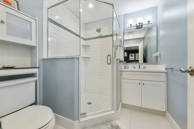 a bathroom with a sink a toilet a mirror and shower