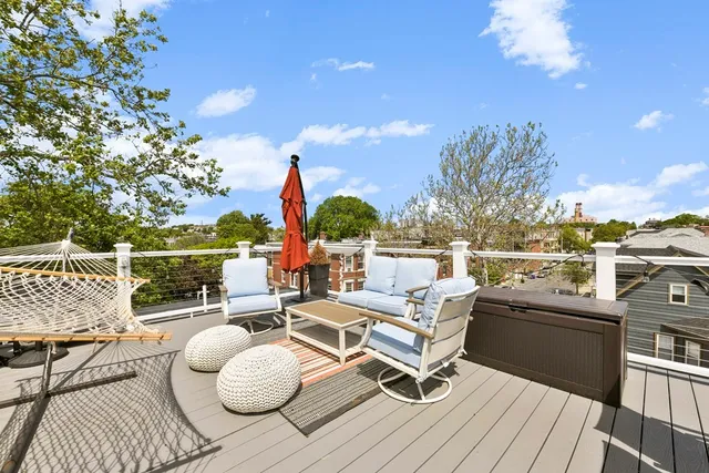 a view of a roof deck with couches fire pit and potted plants
