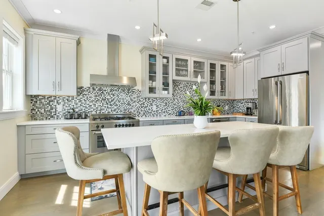 a kitchen with stainless steel appliances granite countertop a table chairs and a refrigerator