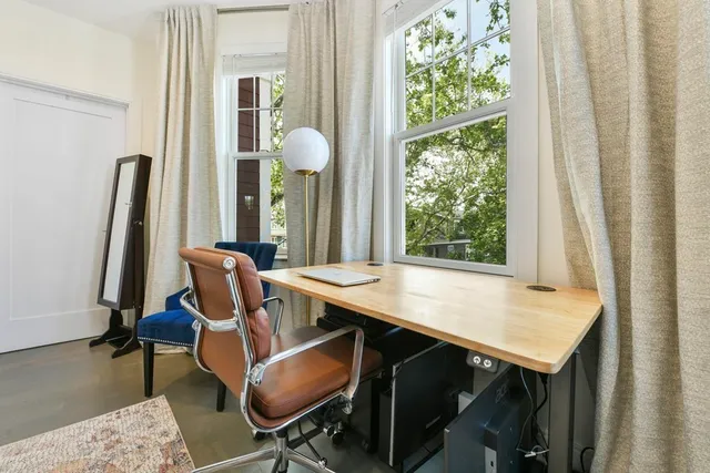 a view of a workspace with furniture and a window