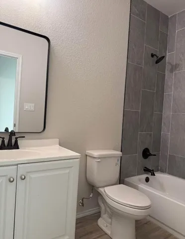 a bathroom with a granite countertop toilet a sink and a mirror