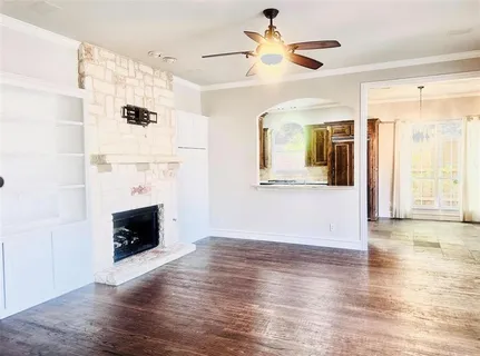 a view of an empty room with wooden floor and a fireplace