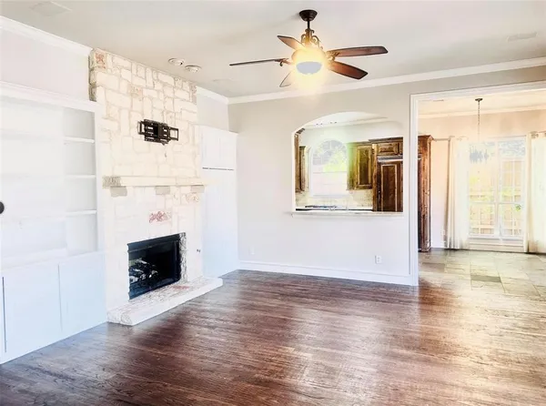 a view of an empty room with wooden floor and a fireplace