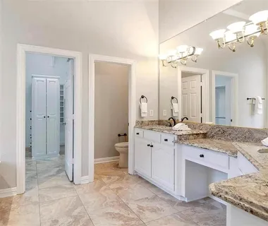 a spacious bathroom with a granite countertop sink a mirror and a shower