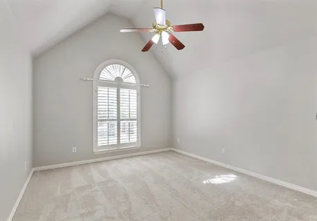 an empty room with ceiling fan and window
