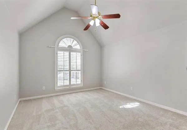 an empty room with ceiling fan and window