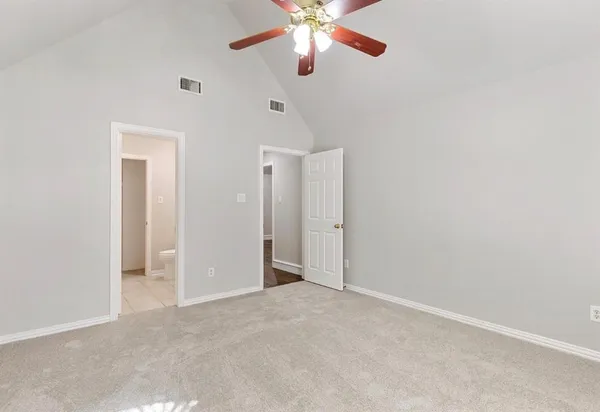 a view of an empty room and chandelier fan