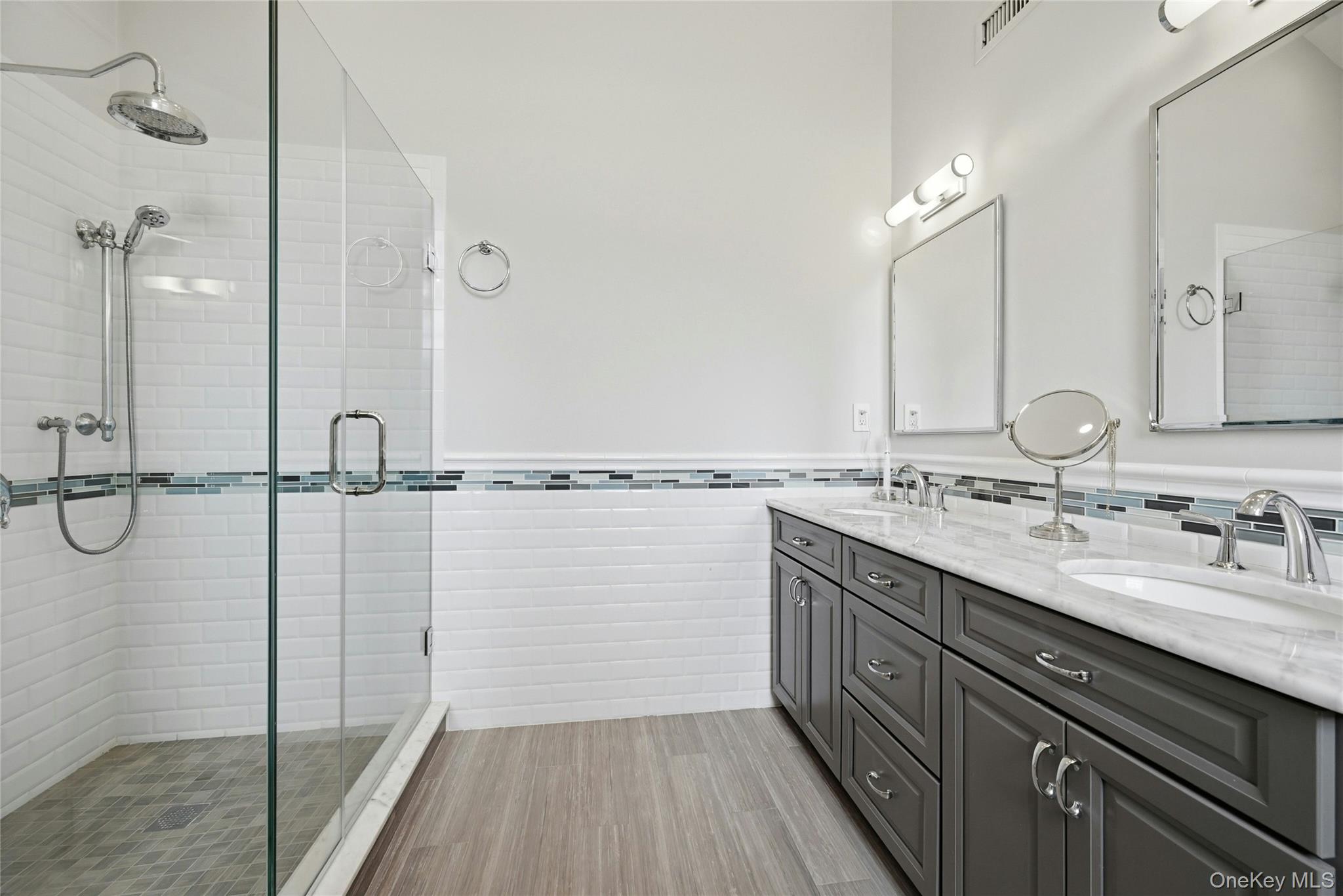 6 Thunder Road Miller Place, NY 11764 - Photo 27 of 50 Another View Of The Primary Bathroom Which Is A Page Out Of Architectural Digest Magazine - A Stunning Free Standing Antique Style Tub With High End Fixtures, Soaring Ceilings With An Accent Circle Topped Window & Chandelier, Oversized Custom Shower With Classic Subway Tiled Walls & Wraparound Frameless Glass Doors (Original Walls Removed When The Bathroom Was Redesigned), All Subway Tiled Walls With Decorative Borders, Custom Dual Sink Marble Topped Vanity, Porcelain Plank Tiled Floors & All Upgraded Fixtures...A True Showplace.