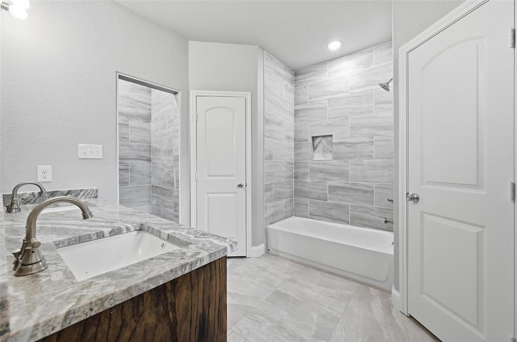 306 Lewis Street Cleburne, TX 76031 - Photo 17 of 20 a bathroom with a granite countertop sink a mirror and a bathtub