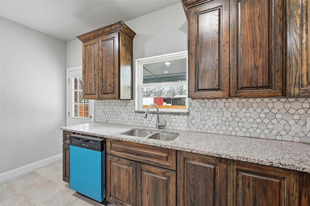 306 Lewis Street Cleburne, TX 76031 - Photo 5 of 20 a kitchen with granite countertop a sink and a wooden cabinets