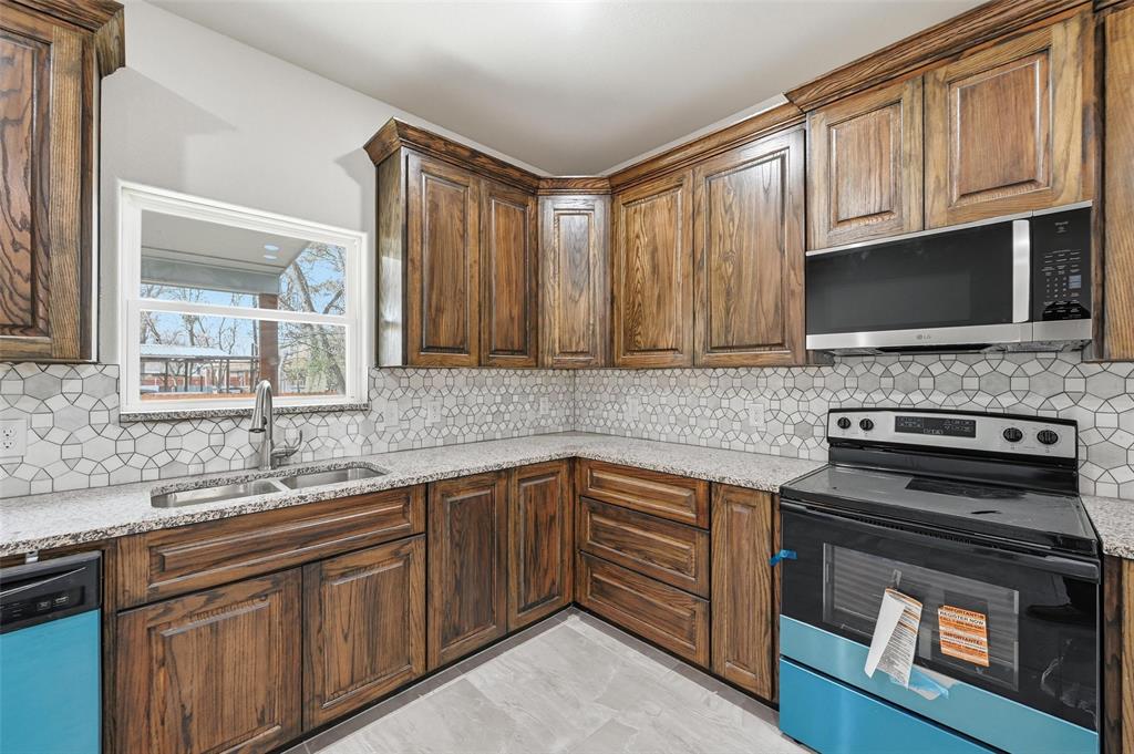 306 Lewis Street Cleburne, TX 76031 - Photo 7 of 20 a kitchen with stainless steel appliances a stove sink microwave and cabinets
