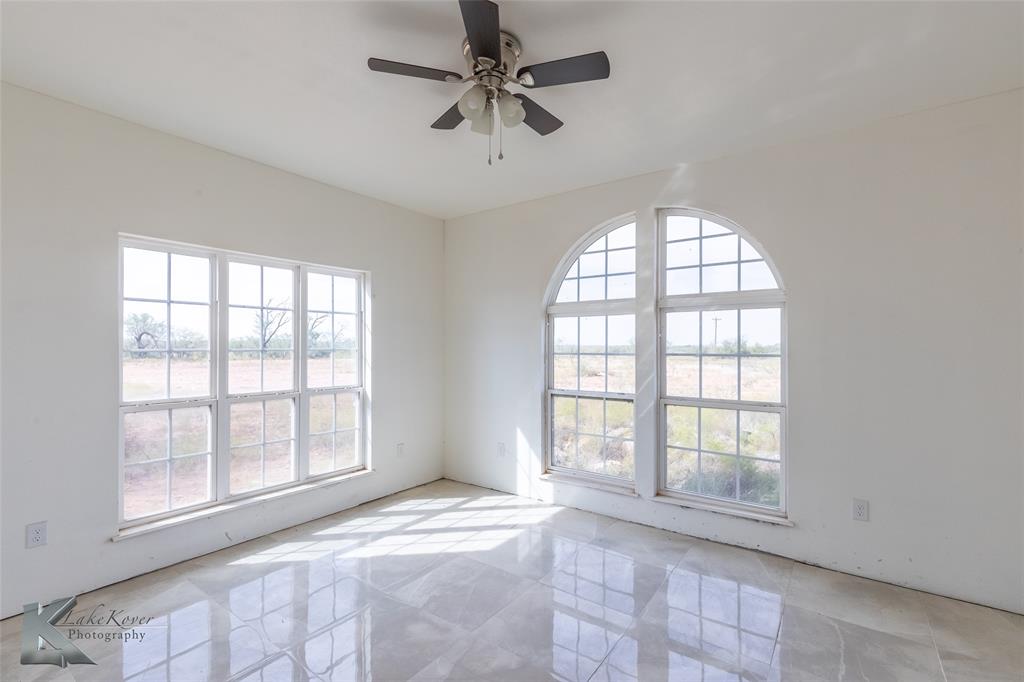 8773 West Lake Road Abilene, TX 79601 - Photo 18 of 40 an empty room with chandelier fan and windows