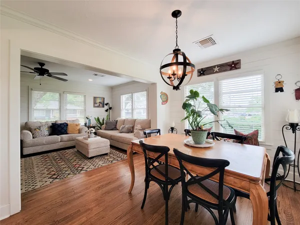 a view of a dining room and livingroom with furniture wooden floor a chandelier