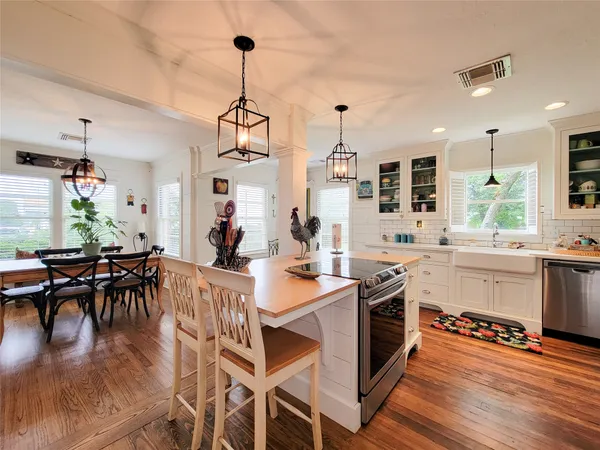 a kitchen with stainless steel appliances granite countertop a stove a sink dishwasher a stove and a dining table with wooden floor