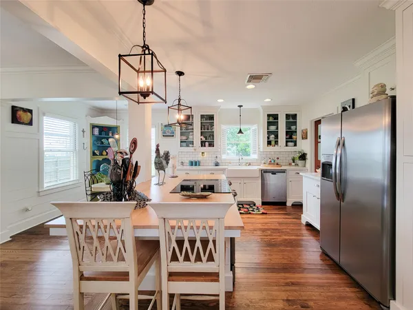 a kitchen with stainless steel appliances a dining table chairs stove refrigerator and microwave