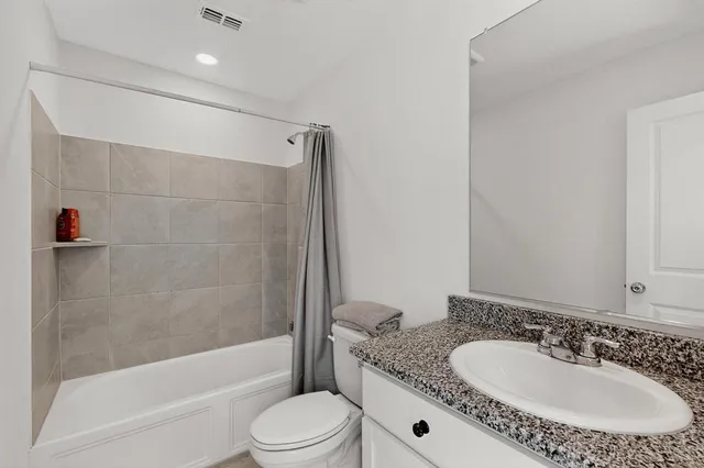 a bathroom with a granite countertop sink a toilet a mirror and shower