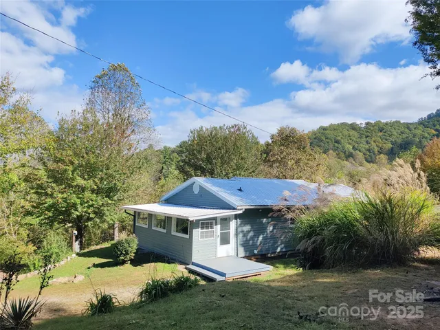 a view of a big house with a big yard and large trees