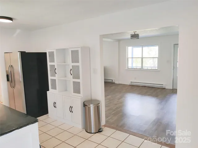 a view of a kitchen with a refrigerator wooden floor and a window
