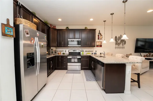 a large kitchen with stainless steel appliances kitchen island granite countertop a refrigerator and a stove top oven