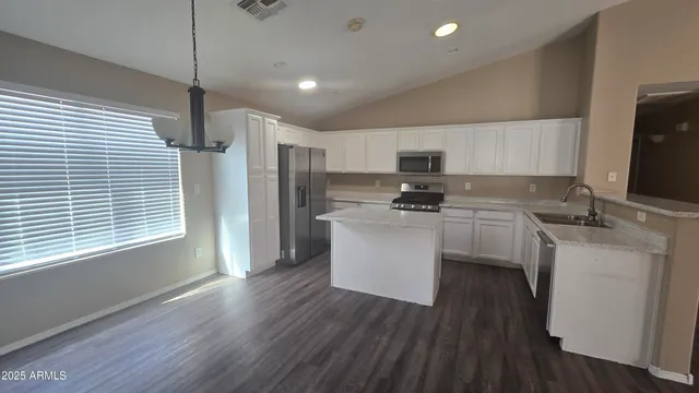 a kitchen with a refrigerator a stove top oven a sink and dishwasher with wooden floor