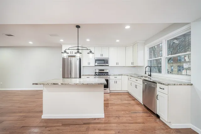 a large kitchen with stainless steel appliances granite countertop a stove a sink and a granite counter tops