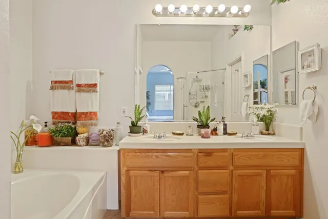 a bathroom with a white tub a sink and a large mirror