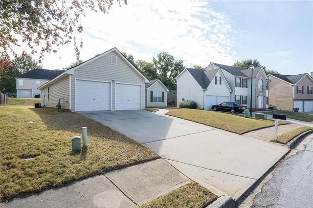 a view of a house with a small yard and large trees