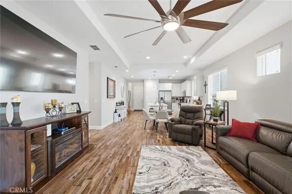 a living room with furniture kitchen view and a wooden floor
