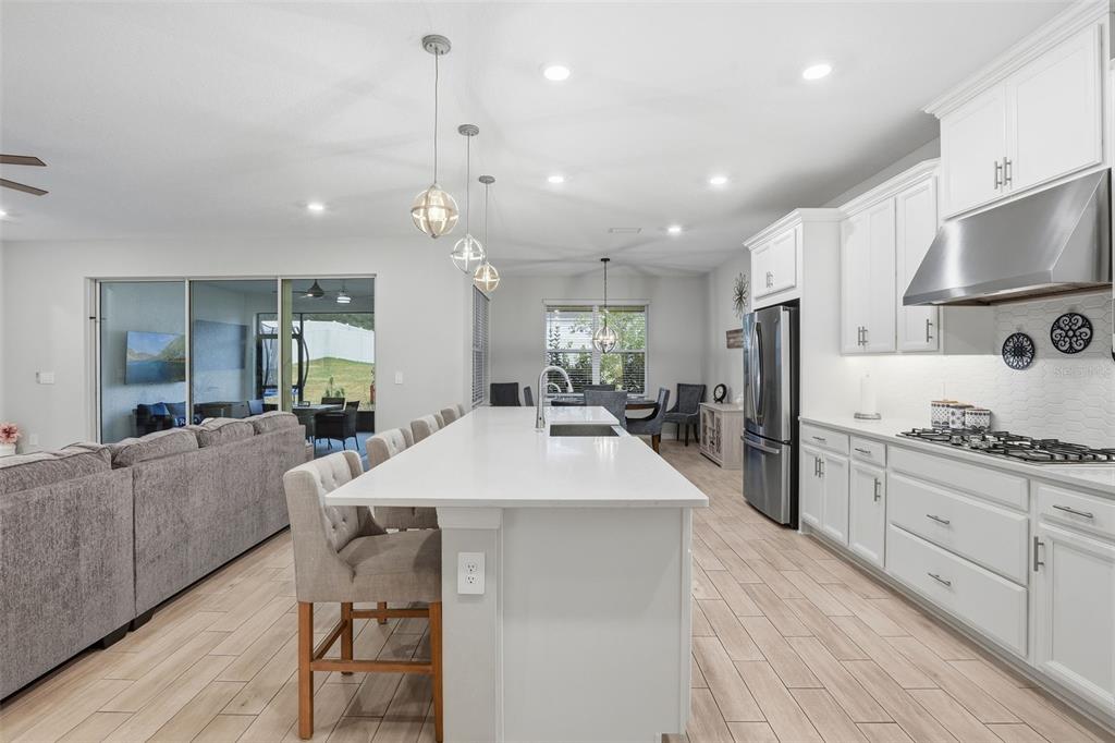 1271 Waterview Ridge Circle Apopka, FL 32703 - Photo 11 of 56 a large kitchen with kitchen island a stove a sink a refrigerator and a dining table with wooden floor
