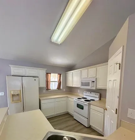 a kitchen with white cabinets and white appliances