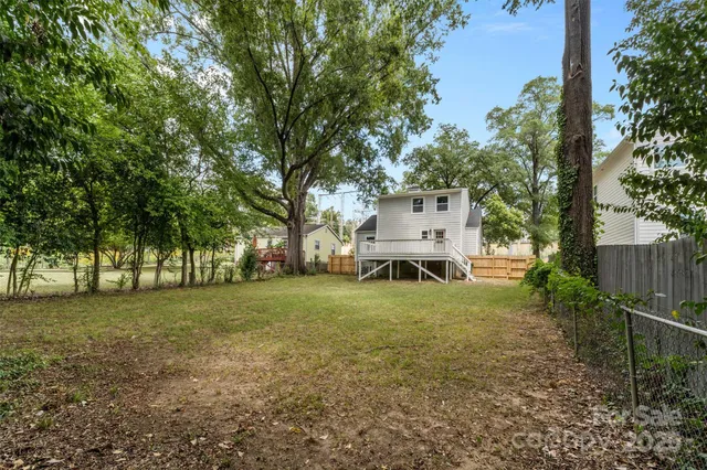 a view of a big yard with large trees and a small barn