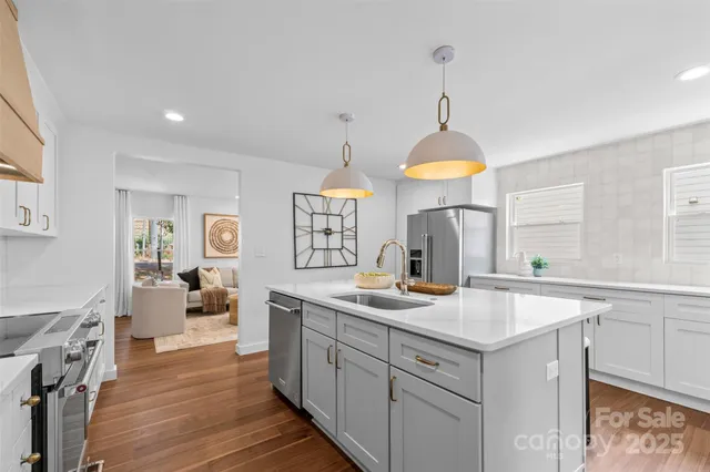 a kitchen with sink stove and white cabinets with wooden floor