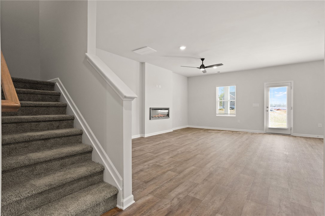 629 Silver Fir Street Piedmont, SC 29673 - Photo 10 of 36 This inviting living space features warm flooring, a modern fireplace, and a staircase leading to additional levels.