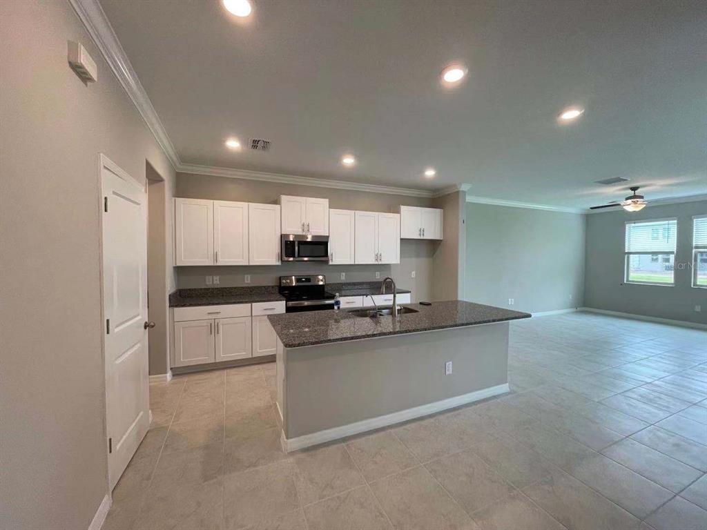 31993 Blue Passing Loop Wesley Chapel, FL 33545 - Photo 2 of 17 a kitchen with stainless steel appliances kitchen island granite countertop a sink and cabinets