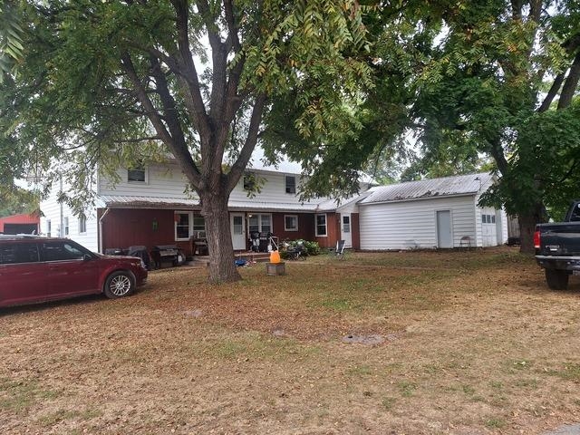 a view of a house with a large tree and a car parked in front of it