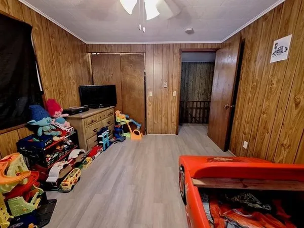 a bedroom with bed a flat tv screen and on a dresser
