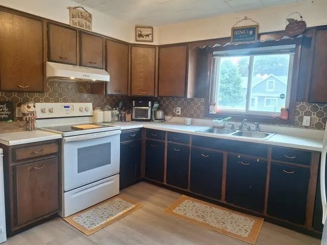 a kitchen with stainless steel appliances granite countertop a sink a refrigerator and a stove