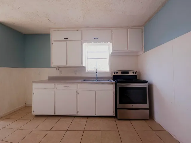 a kitchen with granite countertop white cabinets and stainless steel appliances